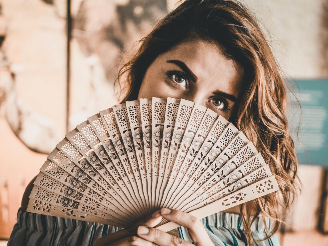 Woman holding a hand-held fan with expressive face